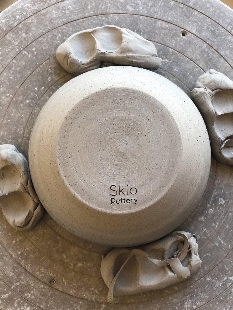 A bowl is trimmed and stamped before firing