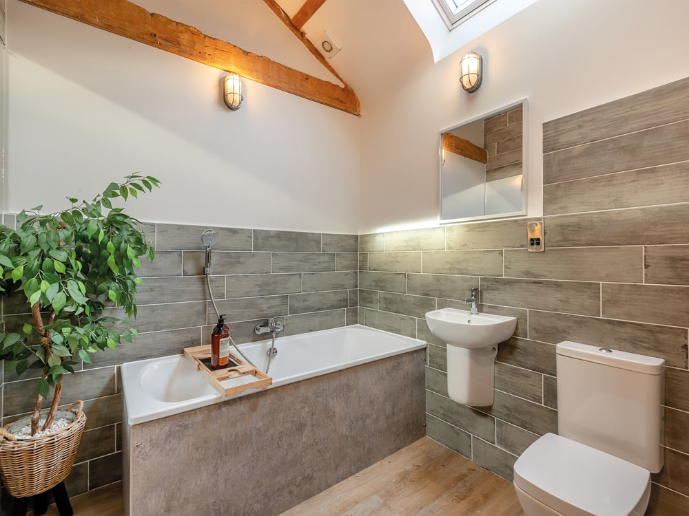 Brick and stone walls, and wood flooring; this spacious bathroom is decorated
with soothing natural and neutral finishes - The Barnacle Goose