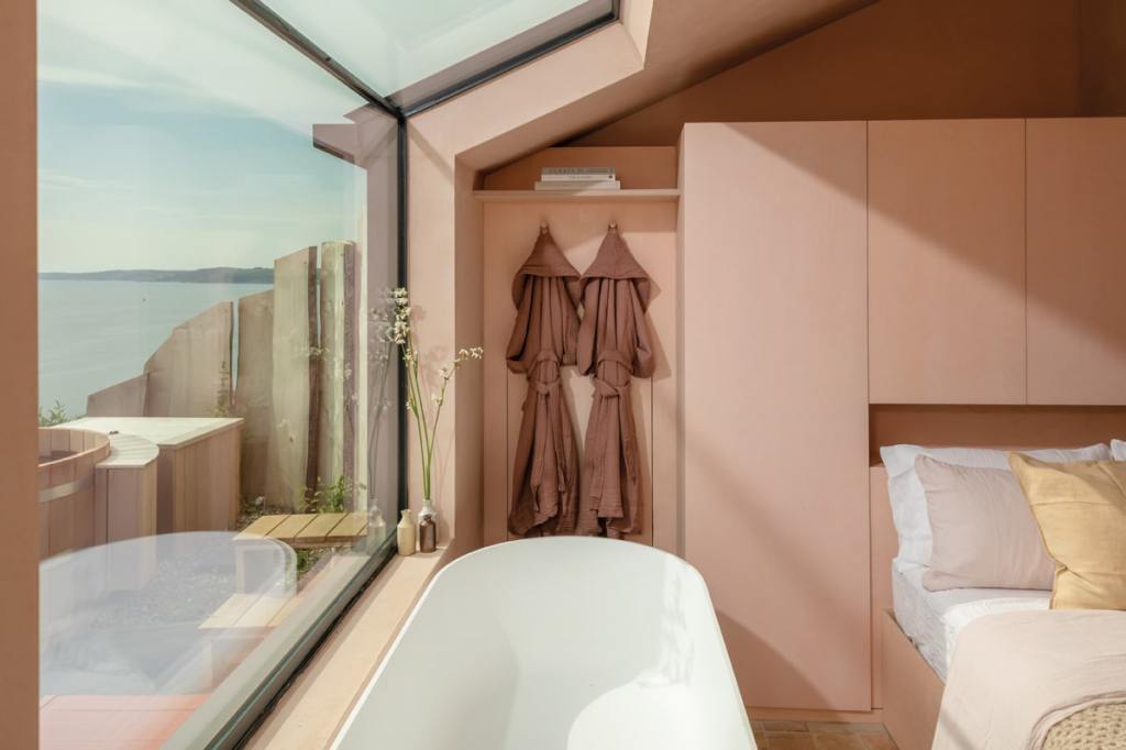 The sky and sea are visible from  the stone bathtub in the bedroom