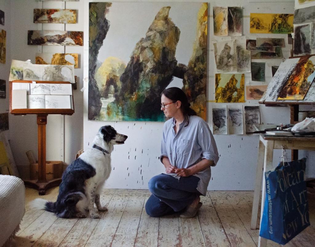 Sarah in her daylit studio, surrounded by the preliminary sketches and smaller paintings she uses as reference for a larger piece. She shares a moment with canine companion Dab, who often accompanies her on her explorations of Cornwall – the collie is ‘not a fan of waves, but keen on a good cliff walk. Photography Harmony Murt