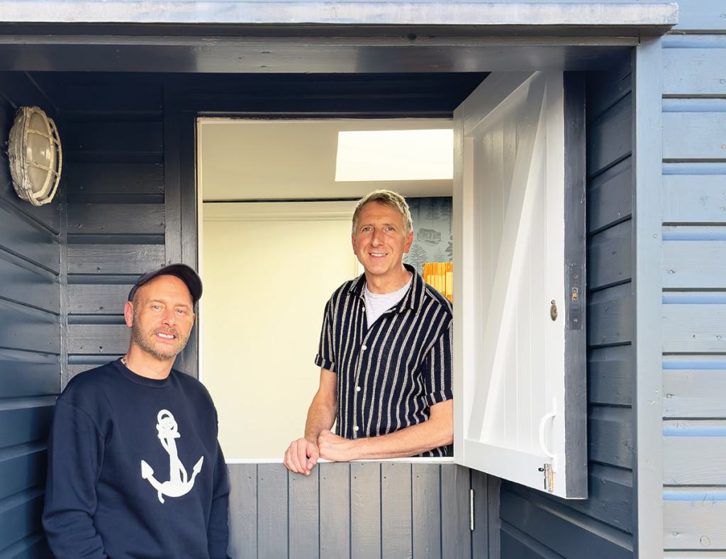 Keith Stephenson (left) and Mark Hampshire of Mini Moderns at their home in Dungeness – a thoughtfully repurposed former railway carriage, with design features that include a stable door for natural light and ventilation 