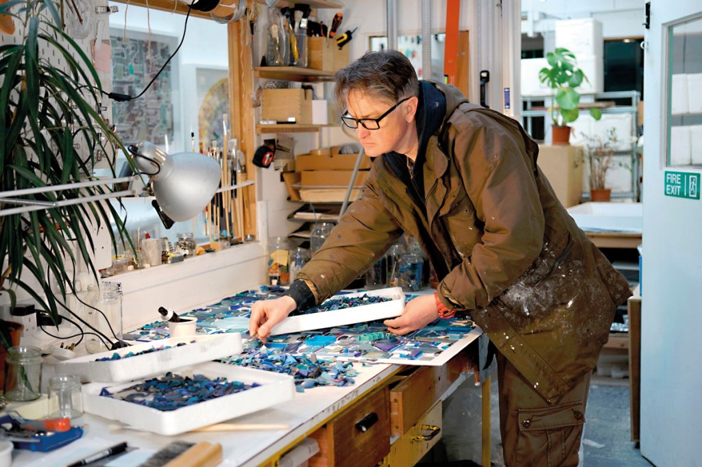 Using tweezers, the artist meticulously selects items from the boxes of marine plastic he has collected over the years